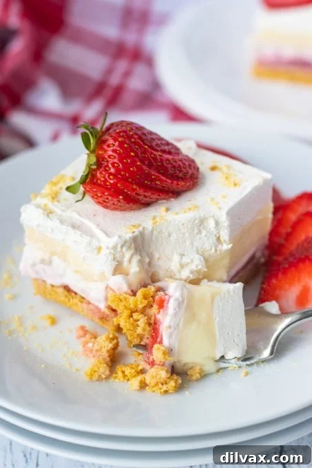 A slice of Strawberry Cheesecake Dream Bar with a bite taken out, showing the layers