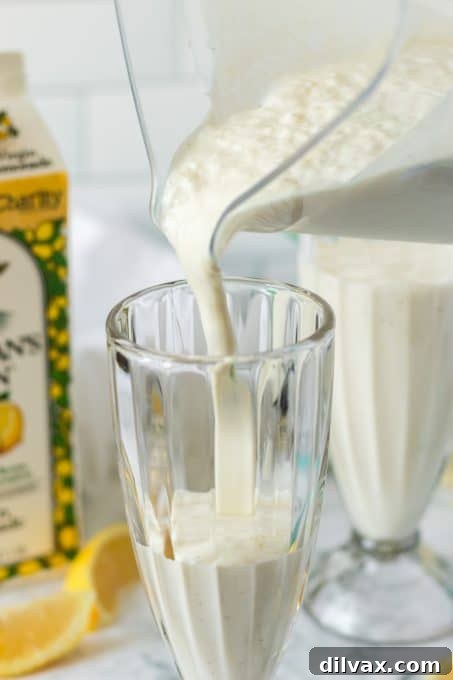 Perfect Frosted Lemonade Dupe: 3 Ingredients, Zero Added Sugar 8 Pouring the blended Lemon Milkshake into a tall, chilled glass for serving.