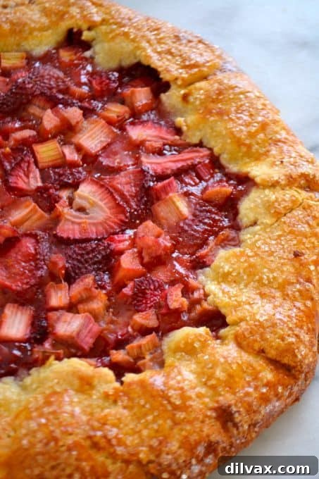 Close-up of a Strawberry Rhubarb Galette cooling on a wire rack, showcasing its golden crust and vibrant fruit filling.