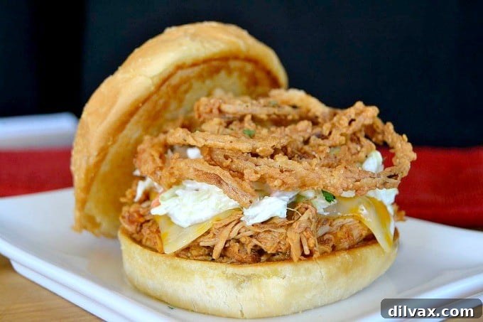 Shredded, slow-cooked barbecue chicken on a kaiser roll with melted cheese, coleslaw, and onion strings
