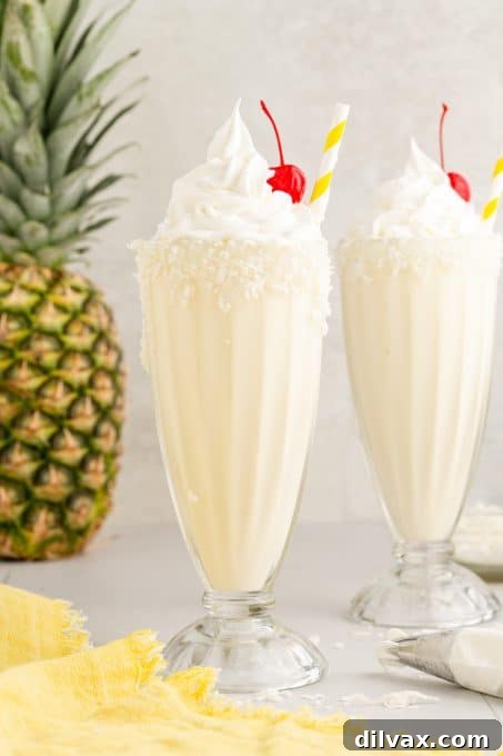 Close-up of a refreshing Pina Colada Milkshake garnished with coconut flakes and a maraschino cherry.