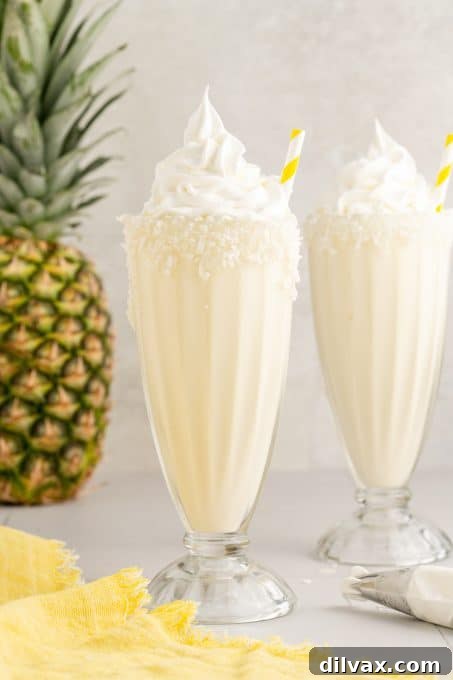 Adding a straw to a finished Pina Colada Milkshake, ready to be enjoyed.