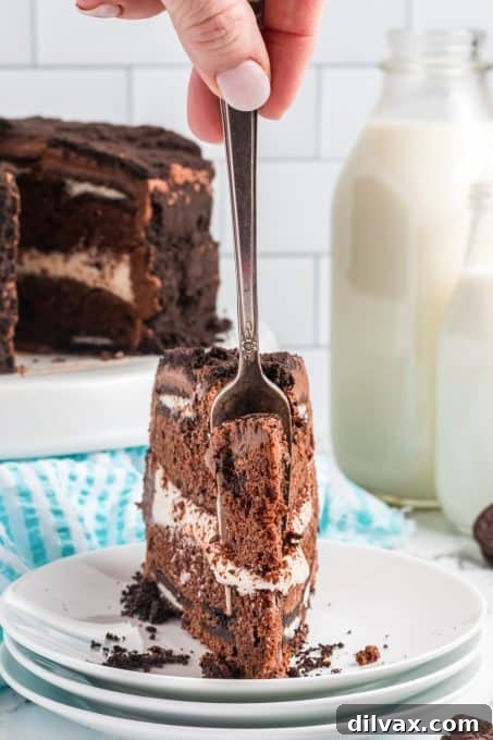 Decadent Oreo Dream Cake 11 A hand taking a generous bite of a freshly sliced Oreo cake, showing the rich texture and delicious layers.