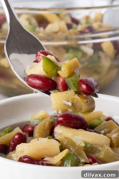 A close-up shot of a single bite of Three Bean Salad on a fork, showing the individual bean types and dressing.