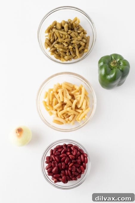 Some of the key ingredients for Three Bean Salad laid out, including canned beans, bell pepper, and onion.