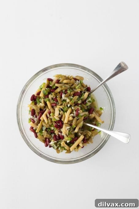 A vibrant bean salad that has been fully tossed in its zesty dressing, ready for chilling.