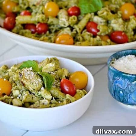 Pesto Chicken Pasta Salad, close-up, showing detailed texture of campanelle pasta, chicken, tomatoes, and mozzarella coated in vibrant pesto.