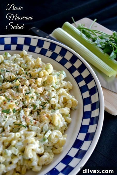 A creamy, classic macaroni salad in a serving bowl, generously garnished with a sprinkle of paprika and fresh parsley, perfect for any summer potluck.