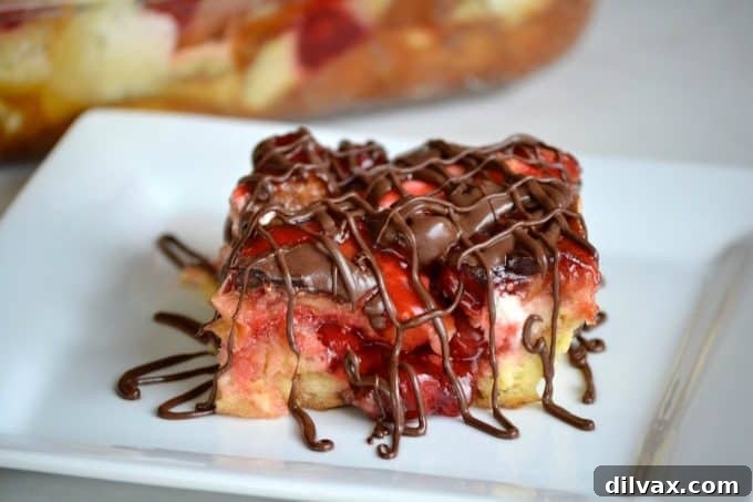 A stunning overhead shot of the baked Chocolate Cherry Cheesecake Bread Pudding, showing its beautiful golden crust, bubbling cherry pockets, and tempting chocolate drizzle, presented in its baking dish.