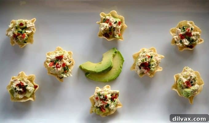 Avocado Tuna Delights 4 Avocado Tuna Salad Bites, garnished with fresh chives and a sprinkle of chili flakes, offer a perfect spicy-creamy balance for any gathering.