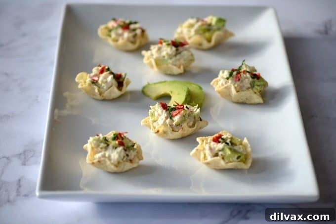 Avocado Tuna Delights 6 Avocado Tuna Salad Bites are garnished with fresh chives and a dash of chili pepper flakes, making them a vibrant and spicy addition to any menu.
