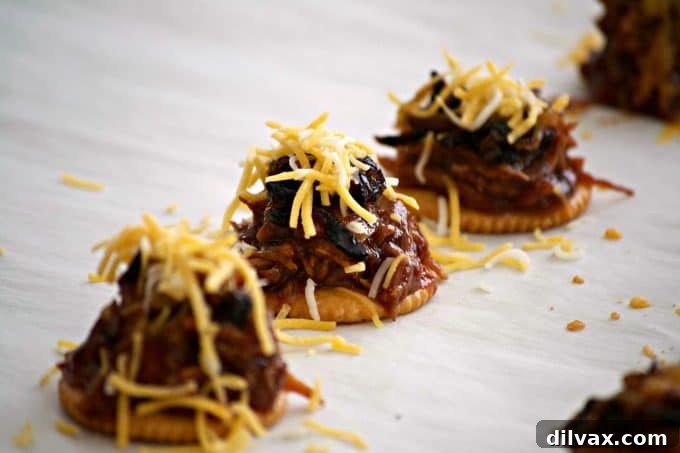 Sweet Heat Cola Pulled Pork Bites 9 RITZ crackers topped with shredded pork, caramelized onions, and cheese, ready for a quick broil to melt the cheese.