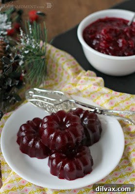 Homemade cranberry sauce in a clear glass bowl, glistening.