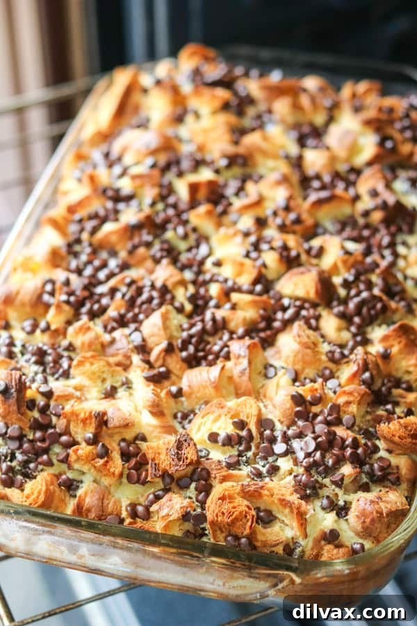 A piping hot baking dish of Chocolate Croissant Baked French Toast, fresh out of the oven, with melted chocolate visible.