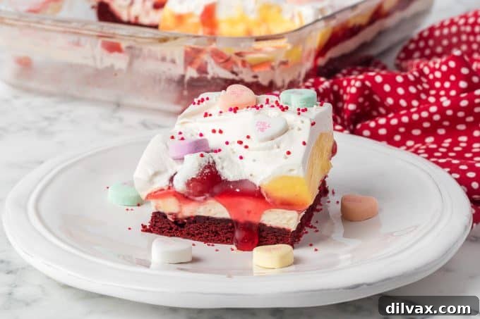 Red Velvet Cherry Dream Bars, a layered dessert with red velvet crust, cheesecake, cherries, pudding, and whipped cream.