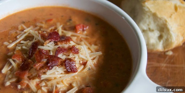 Creamy Tomato Basil Soup served in a small white bowl with a spoon, highlighting its smooth texture and appetizing appeal.