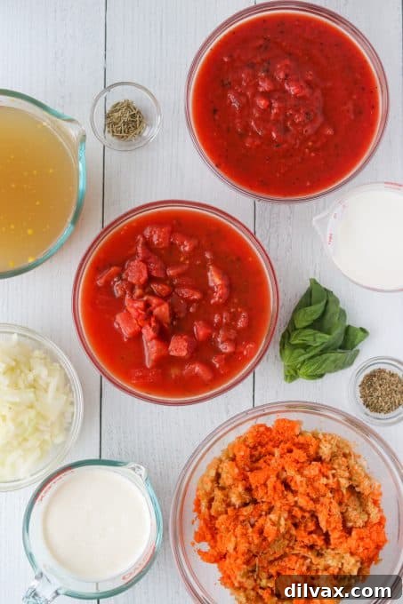 Various fresh ingredients laid out on a wooden cutting board, including canned tomatoes, fresh basil, celery, carrots, and onion, ready for making homemade tomato soup.