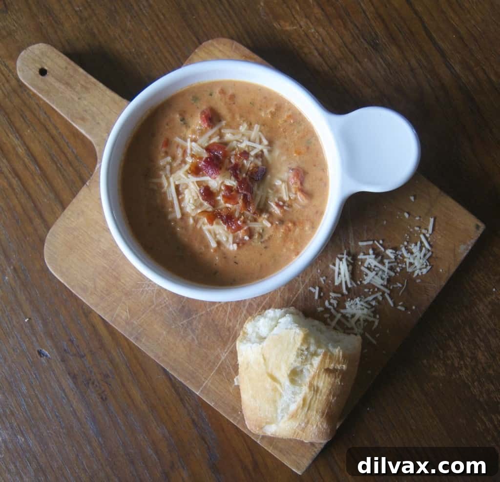 Large bowl of creamy tomato basil soup with a swirl of cream and fresh basil, inviting and delicious.