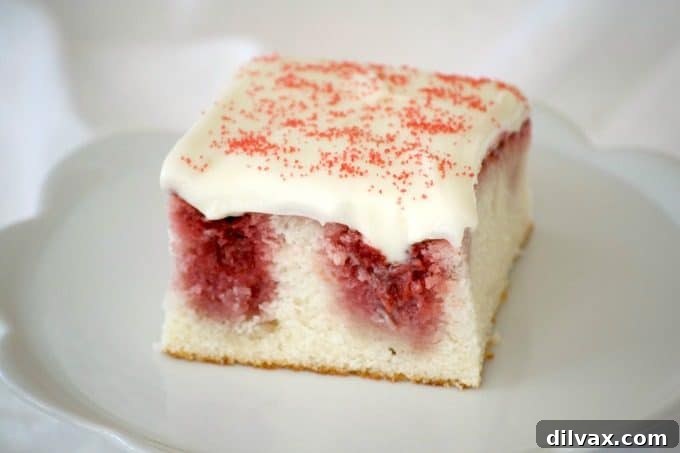 A delicious Strawberry Poke Cake made from scratch with a white cake, fresh strawberry sauce and a rich cream cheese frosting, perfect for Valentine's Day or any day dessert.