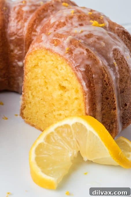 Gigi's Effortless Lemon Cake 4 A delectable slice of Easy Lemon Cake, generously drizzled with homemade lemon glaze, garnished with fresh lemon zest and a sprig of mint, highlighting its freshness.