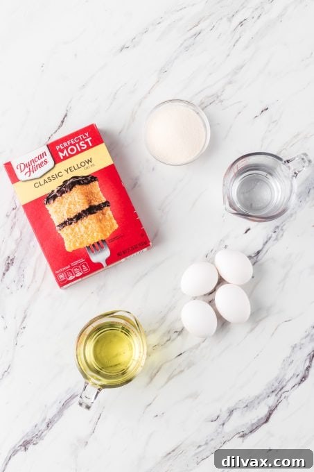 Gigi's Effortless Lemon Cake 5 A collection of simple ingredients arranged on a counter: a yellow cake mix box, lemon gelatin, fresh eggs, cooking oil, and a bowl of hot water, ready for baking Easy Lemon Cake.