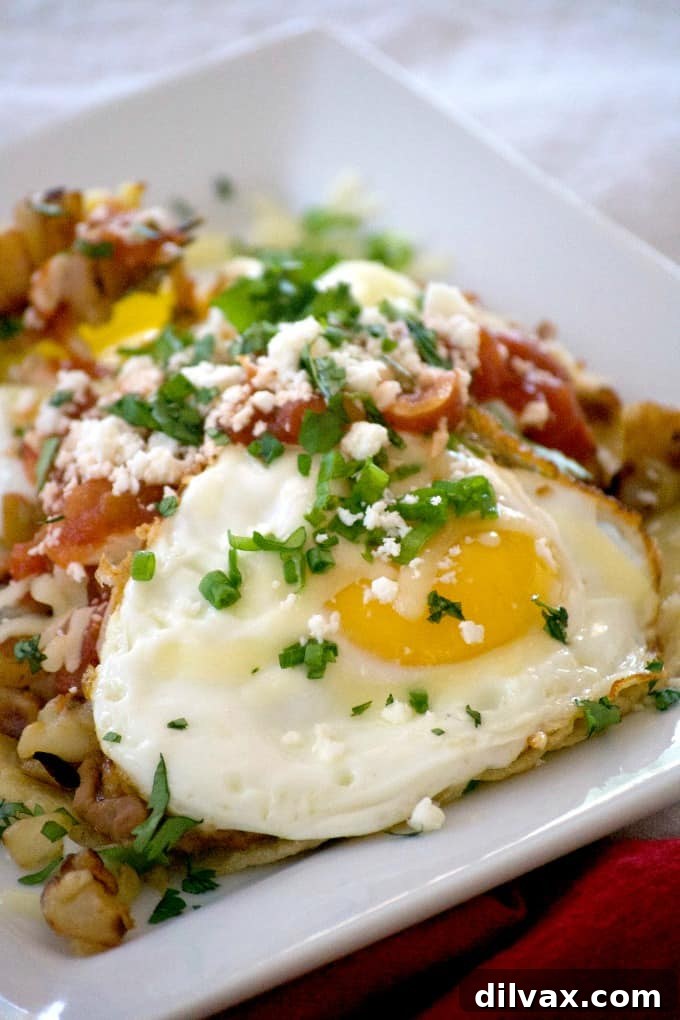 Loaded Huevos Rancheros are tortillas topped with refried beans, Potatoes O'Brien, salsa, eggs and cheese - a hearty breakfast that's full of great flavor!