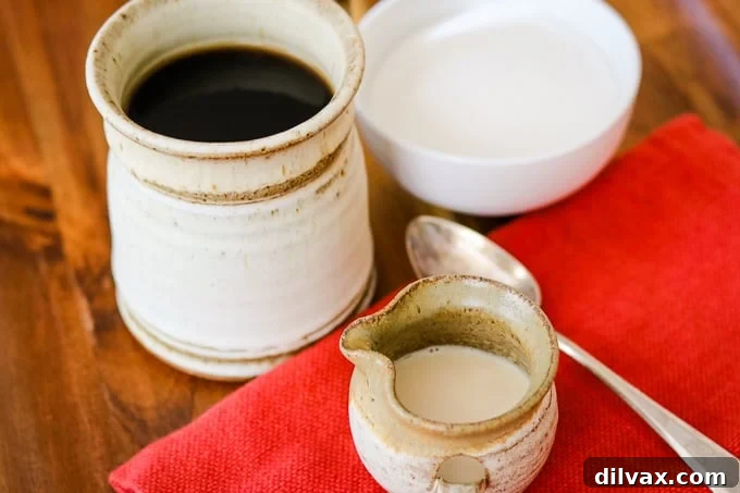 A glass of homemade French Vanilla Coffee Creamer next to a cup of coffee.