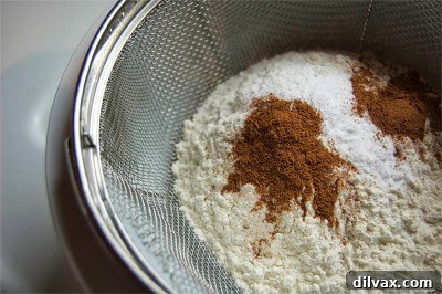 Mixing the sifted dry ingredients into the wet ingredients in a stand mixer bowl.