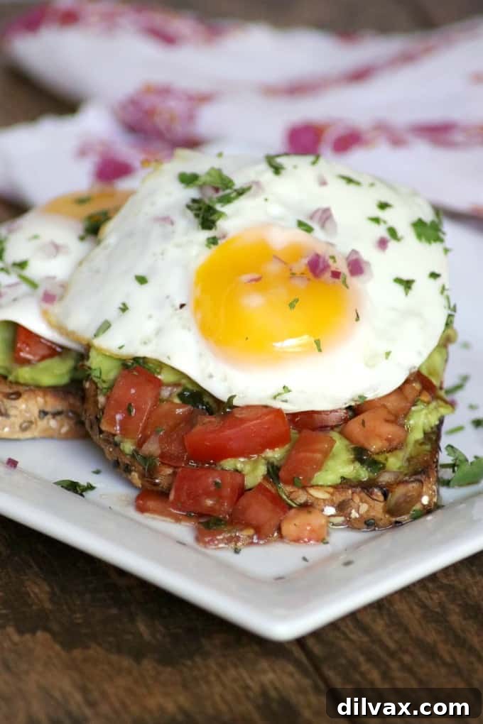 Close-up of Bruschetta Fried Egg Avocado Toast with a runny yolk, showcasing fresh ingredients for a healthy breakfast.