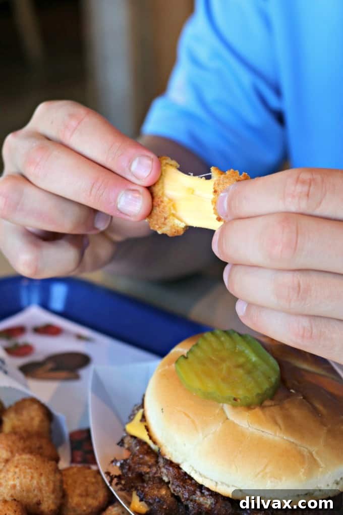 National Cheese Curd Day: Celebrate at Culver's 5 A close-up shot showing a cheese curd being stretched, with long, delicate strands of melted cheddar