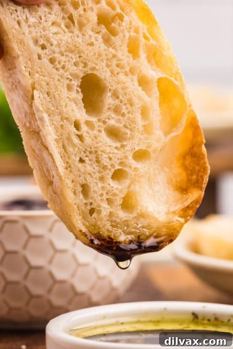 A close-up shot of olive oil and balsamic vinegar being drizzled onto a slice of Ciabatta bread.
