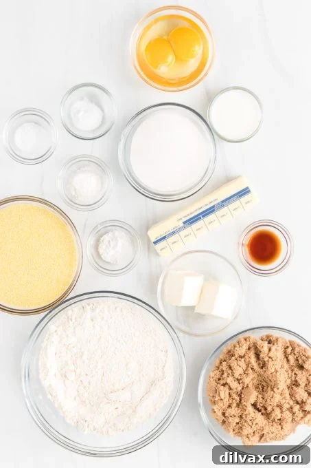 A collection of baking ingredients, including flour, cornmeal, butter, eggs, and sugars, neatly arranged on a counter.