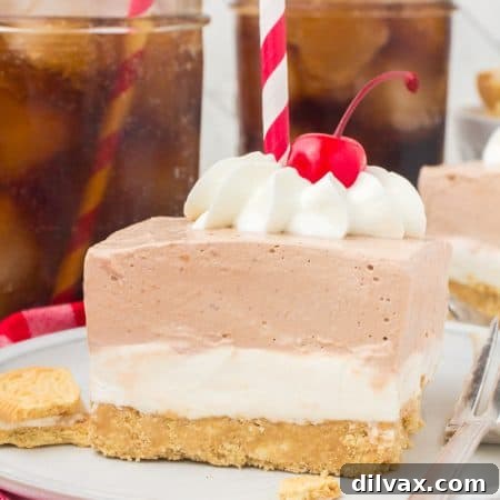 A layered dessert with whipped cream, a long stem cherry, and red and white drinking straw on top.