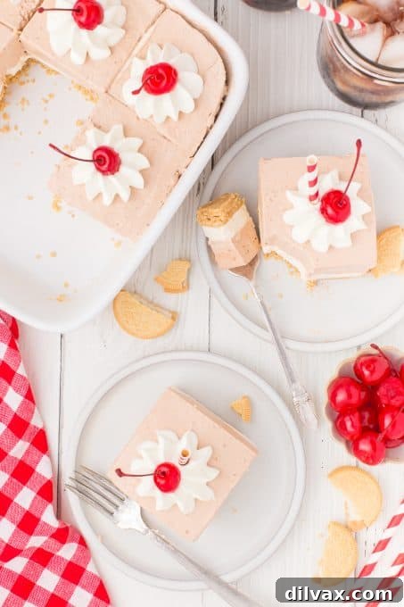 Looking down at a light brown gelatin dessert topped with whipped cream and long stem cherries.