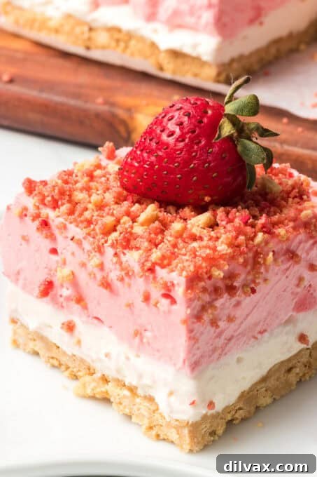 A single strawberry shortcake bar standing upright, showcasing its distinct layers and topped with a fresh strawberry.