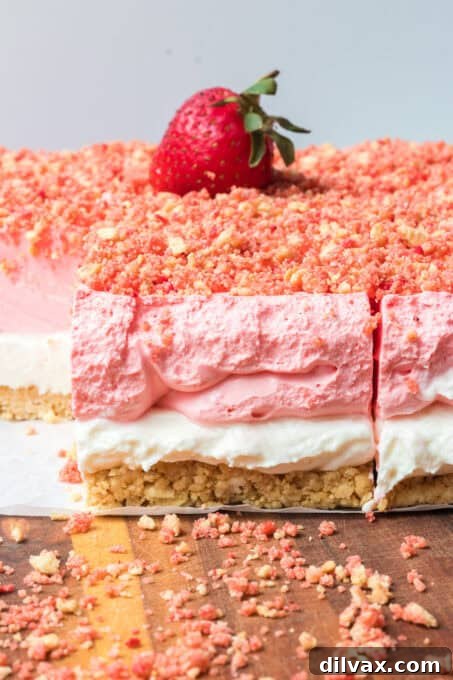 A close-up shot of the creamy strawberry gelatin layer of the dessert, topped with a slice of fresh strawberry.