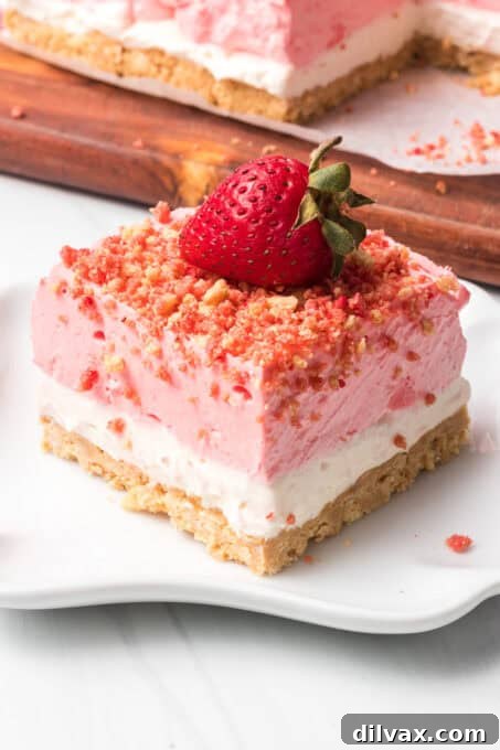 A single no-bake strawberry crunch bar on a white plate, garnished with a fresh strawberry.