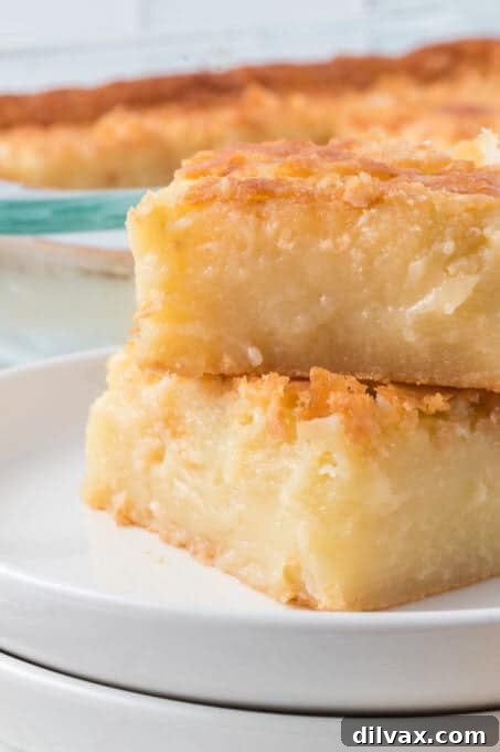 A single square of Butter Mochi on a white plate, showing its chewy texture.