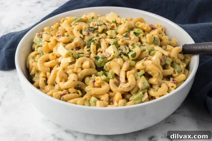 A white serving bowl of Chick-fil-A Macaroni Salad placed on a blue napkin, ready for a summer picnic.