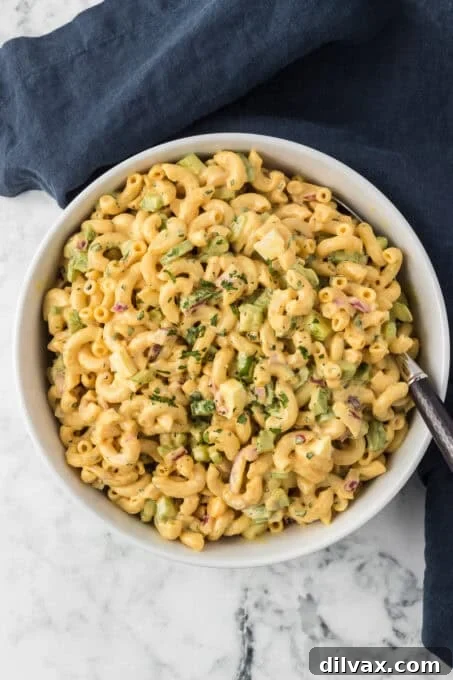 A serving spoon scooping a portion of the creamy Chick-fil-A Macaroni Salad from a large bowl.