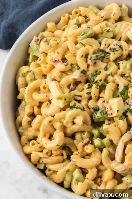 A close-up shot of the finished Chick-fil-A Macaroni Salad in a white bowl, garnished with fresh parsley.