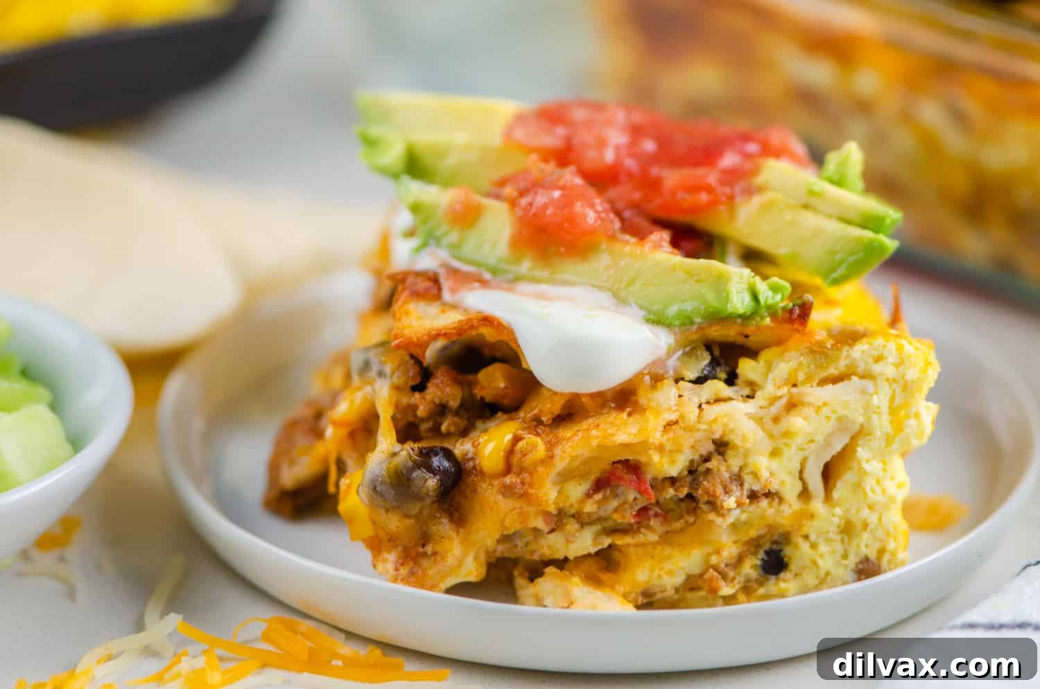 A slice of cheesy Mexican Breakfast Casserole with chorizo, eggs, and peppers on a white plate.