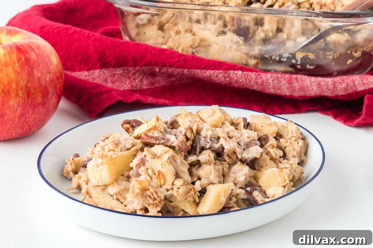 A serving of Baked Apple Oatmeal in a bowl, topped with fresh apple slices and nuts.
