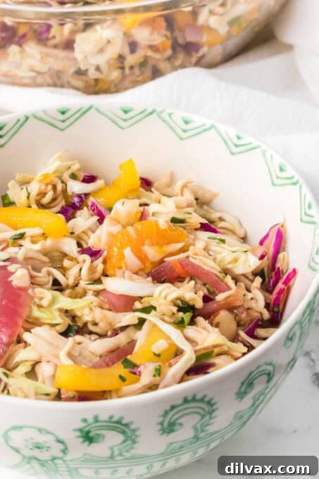 A bowl of an Asian inspired chicken salad with dry ramen noodles.