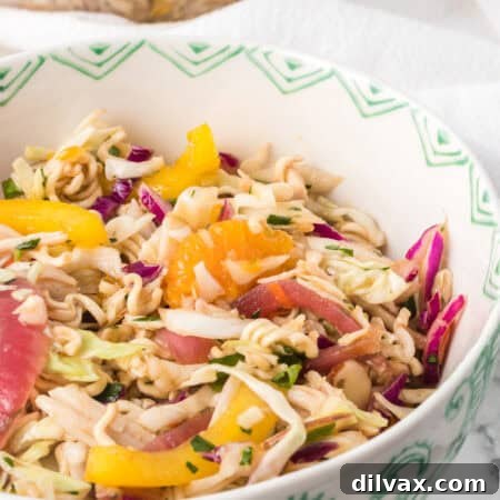 A bowl of an Asian inspired chicken salad with dry ramen noodles.