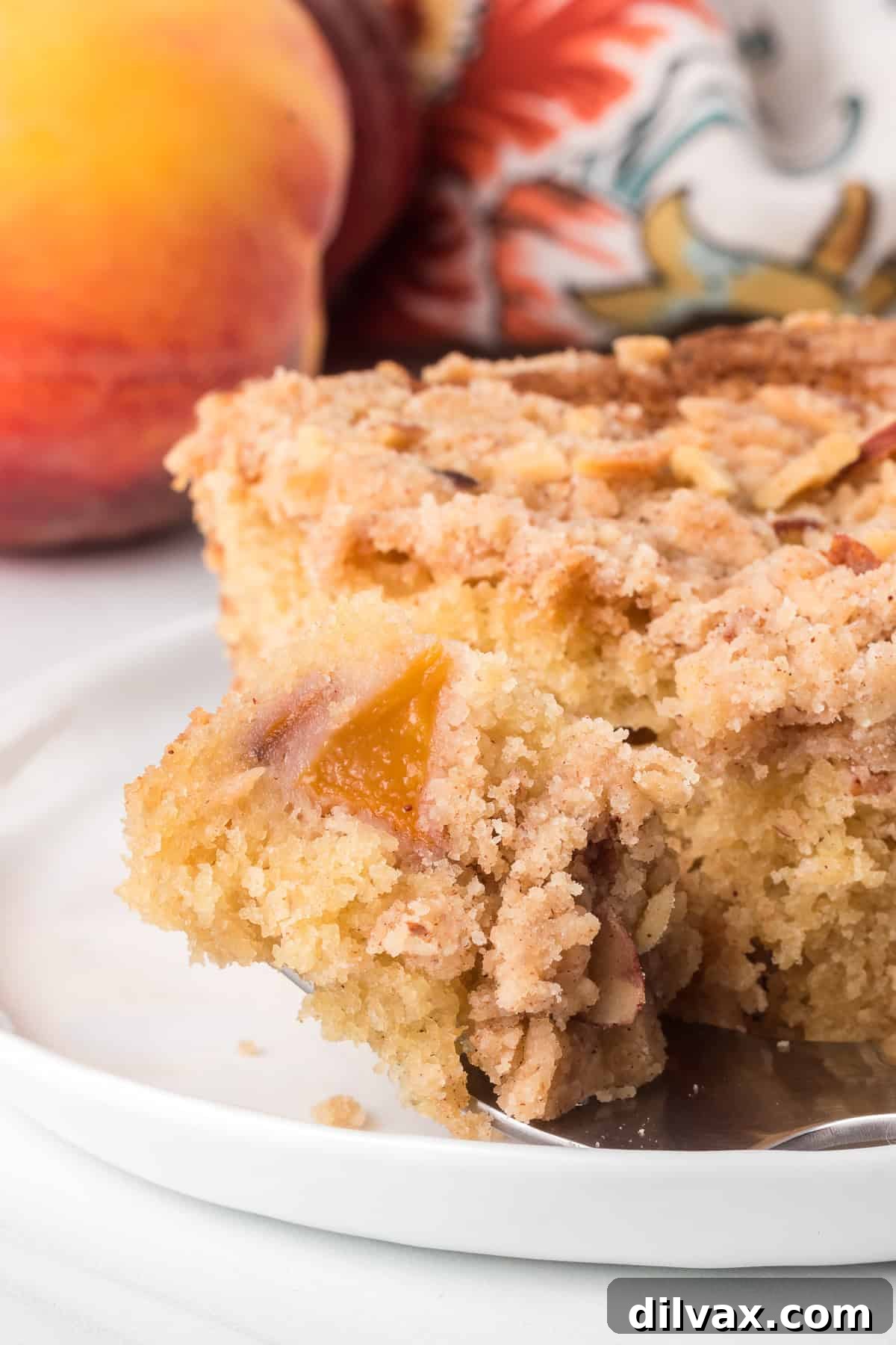 A bite taken out of a peach cake dessert.